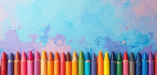 Colorful crayons arranged in a line on a textured blue purple background. Artistic drawing tools create a vibrant playful border for creative projects and kids art classes.