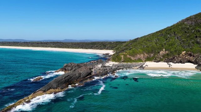 Aerial video capturing gentle ocean waves rolling onto the wide sandy shoreline at Janies Corner, Seven Mile Beach in Forster