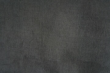 Close-up of dark gray fabric.  Texture is visible.  Material appears soft.  Subtle sheen is present.  Suitable for backgrounds or textiles
