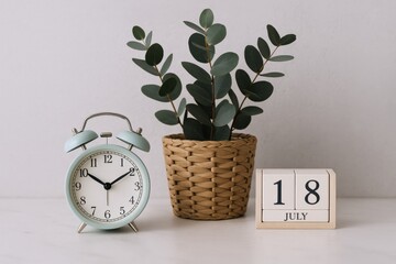 Elegant Still Life with Clock, Eucalyptus Plant, and Calendar Displaying July 18th on a White Background