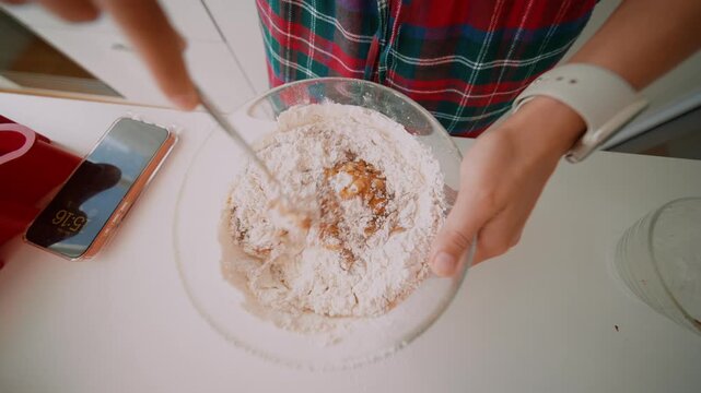 Person in kitchen expertly blending cookie dough with focus and precision