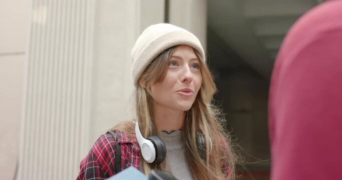 Diverse women smiling and laughing after interviewer question at walkway with beanie, headphones