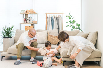 Grandfather and grandmother playing with their granddaughter in the living room at home (babysitting, taking care of, working couple)
