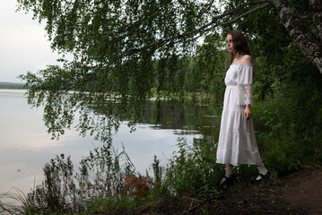 Elegance by the Lake: Woman in White Off-Shoulder Dress Among Birch Trees