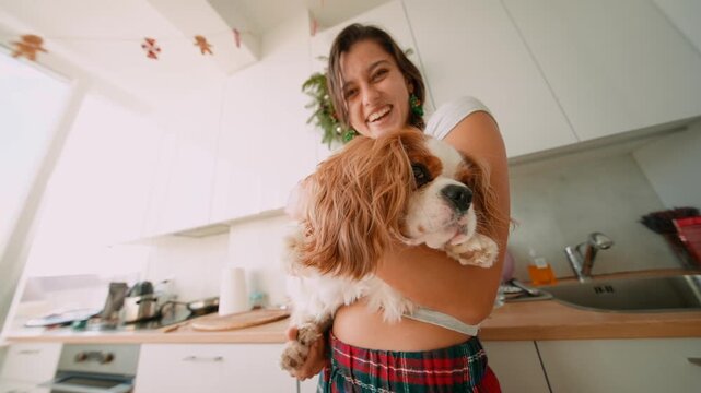 Casual portrait of woman cuddling her spaniel inside kitchen