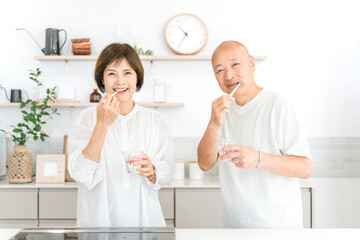 Fototapeta premium キッチンで歯を磨くシニア夫婦（デンタルケア,口臭ケア） 