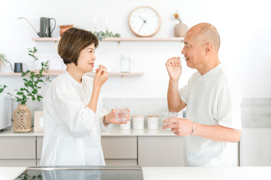 Senior couple brushing their teeth in the kitchen (dental care, bad breath care)
