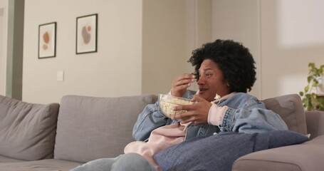 woman watching show, picking popcorn on sofa as movement causing popcorn spilling, wiping tears - Powered by Adobe