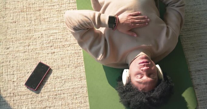 Smartphone appearing at left edge starting camera zooming in on man lying on green mat meditating