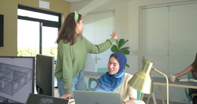 Diverse female team collaborating on 3D floorplan at desk for design review, colleague joining