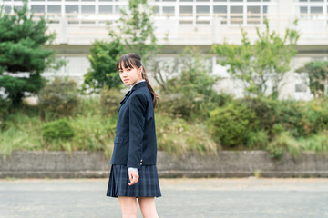 Junior high school, high school, and elementary school students in uniform standing in front of the school building
