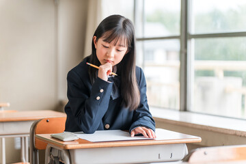 学校の教室・塾の授業でテストを受ける小学生,中学生,高校生の女の子
