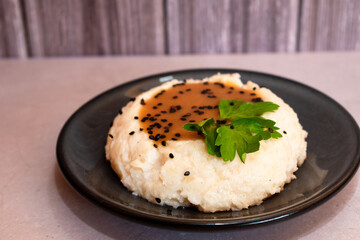 Imagen horizontal de un elegante plato con puré de papa con salsa en medio en un fondo de madera
