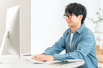 A man using a computer at home to telework, online seminar, side job, video editing