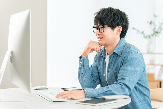A man using a computer at home to telework, online seminar, side job, video editing
- Powered by Adobe