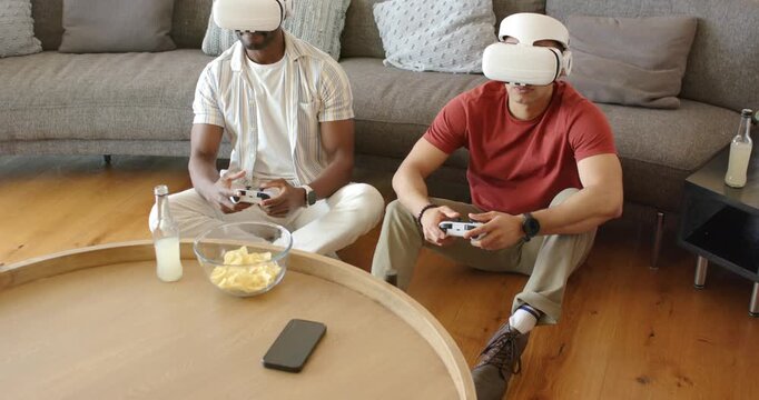 Diverse male friends putting on VR headsets, pressing buttons on controllers to play game at home