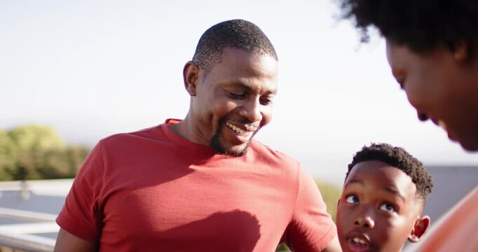 After man smiling at boy African American family leaning against roof railing pointing to show hill