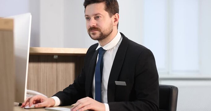 Receptionist working on computer at reception desk indoors