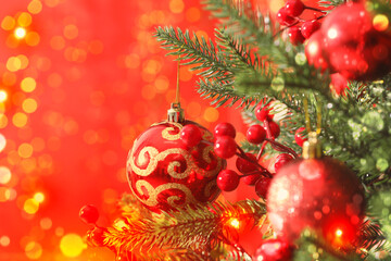 Obraz premium Merry Christmas and Happy Winter Holidays greeting card. Fir tree with festive balls and bokeh lights on red background