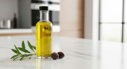 Clear glass bottle of golden olive oil with fresh olives rests on a marble surface in a modern kitchen setting, ready for culinary use.