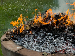 dangerously hot orange and red flames with dense black smoke consuming wood and embers