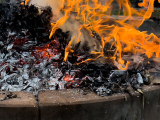 dangerously hot orange and red flames with dense black smoke consuming wood and embers