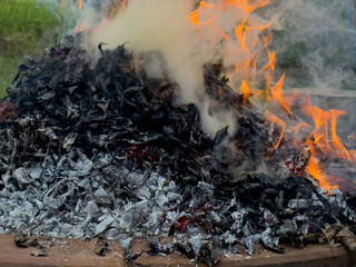dangerously hot orange and red flames with dense black smoke consuming wood and embers