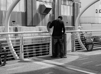 Homeless man on the bridge going through rubbish bin, looking for food