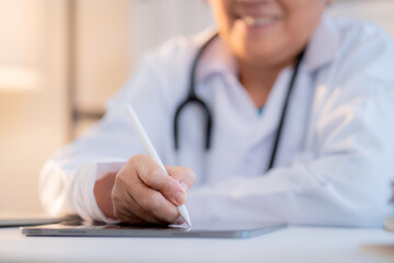 Close up senior doctor writing prescription or document on tablet in clinic office, managing patient record, healthcare and diagnosis, elderly female physician writing on tablet, medical concept.