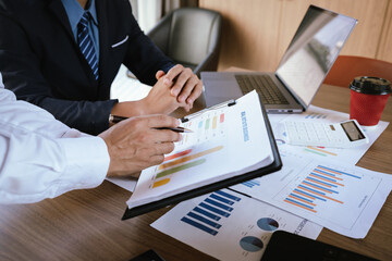 Business team analyzing financial charts and using a calculator during a meeting.