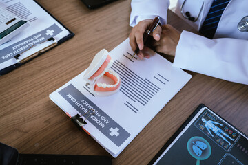 Dental professionals discussing treatment plans with a tooth model and medical documents during a meeting.