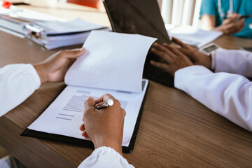 Dental professionals discussing treatment plans with a tooth model and medical documents during a meeting.