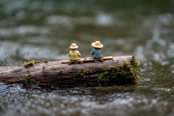 two figurines sitting on a log in the water