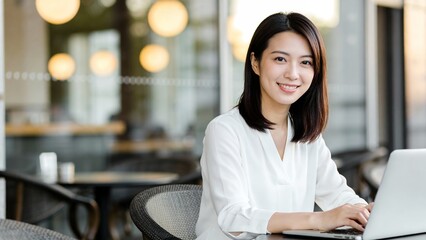 カフェのテラス席でノートパソコンの画面を見つめる女性