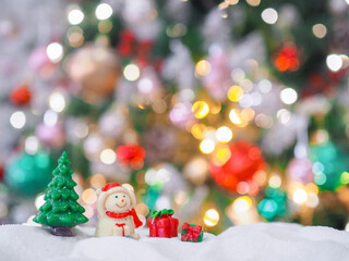 Close-up of tiny pine trees and snowman with Christmas light background
