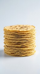 Tall stack of golden flatbreads rests on a clean white surface.