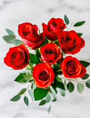 Obraz premium A bouquet of vibrant red roses with green leaves on a marble background.
