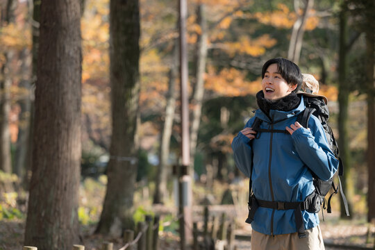 A young man gazing up at the scenery while hiking through autumn and winter mountains ablaze with foliage An image of outdoor excursions and leisure activities