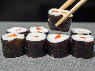 Delicious Sushi Rolls with Chopsticks on Gray Surface