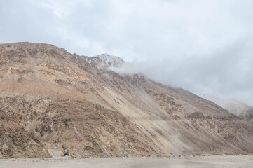 A dry rocky valley in Ladakh with barren mountains, rugged terrain, and a dried river trail under clear sky. Minimal, raw landscape perfect for travel, geography, adventure and Himalayan themes.