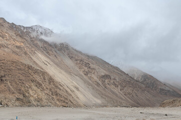 A dry rocky valley in Ladakh with barren mountains, rugged terrain, and a dried river trail under clear sky. Minimal, raw landscape perfect for travel, geography, adventure and Himalayan themes.