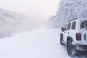Snow covers the landscape while a vehicle sits by the road in a winter scene. High quality photo