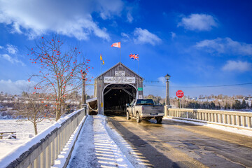 A  small truck drives into the  historic Hartland Covered Bridge National Historic Site in winter New Brunswick Canada and crosses the St. John river.