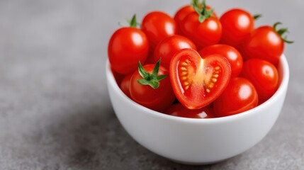 Fresh cherry tomatoes in a white bowl, showcasing vibrant red colors, with one cut tomato revealing a heart shape.