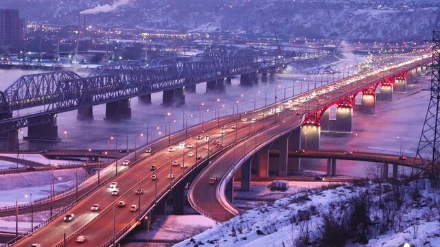 Beautiful bridges in the night illumination. Nikolaevsky Fourth Bridge in Krasnoyarsk, Russia and the railway bridge over the Yenisei River. Traffic and urban transport movement at dawn. High quality