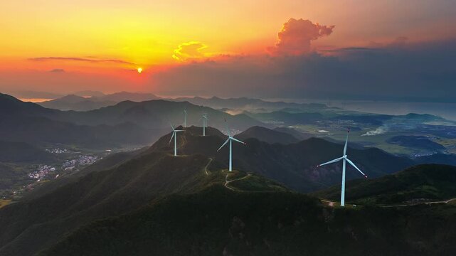 Aerial shot of wind turbines farm on mountain ridge with beautiful sky clouds at sunset 