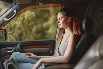 A contemplative young woman in a casual outfit sits in a car, reflecting on life amidst nature s beauty, evoking tranquility and introspection