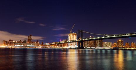 Obraz premium View of Manhattan Bridge New York city skyline at night with lights reflecting on water