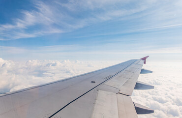 Obraz premium View from the airplane window at a beautiful cloudy sky and the airplane wing