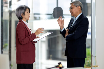 Asian business professionals legal consultants discuss important documents in modern office setting for strategic planning and advice